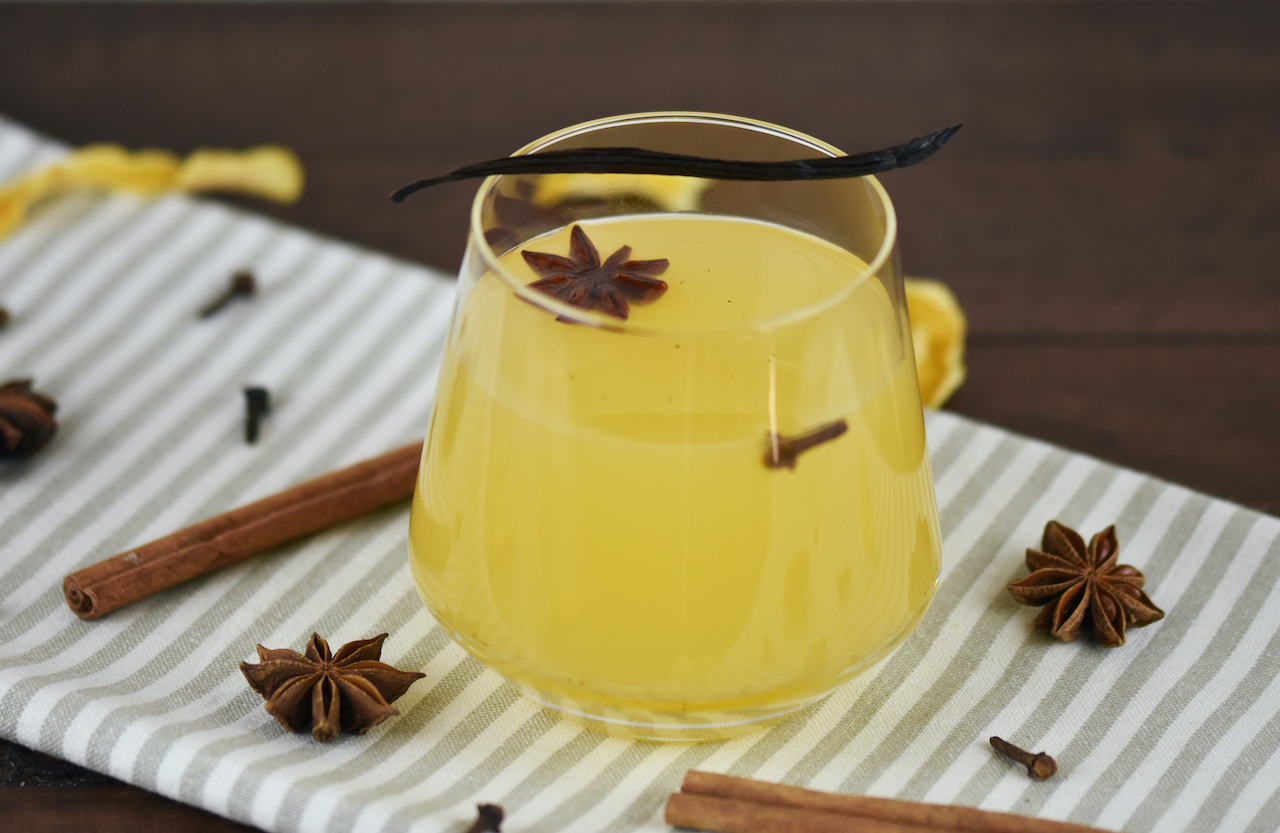 Weißer Glühwein mit Vanille und Orange in einem Glas ohne Stiel.