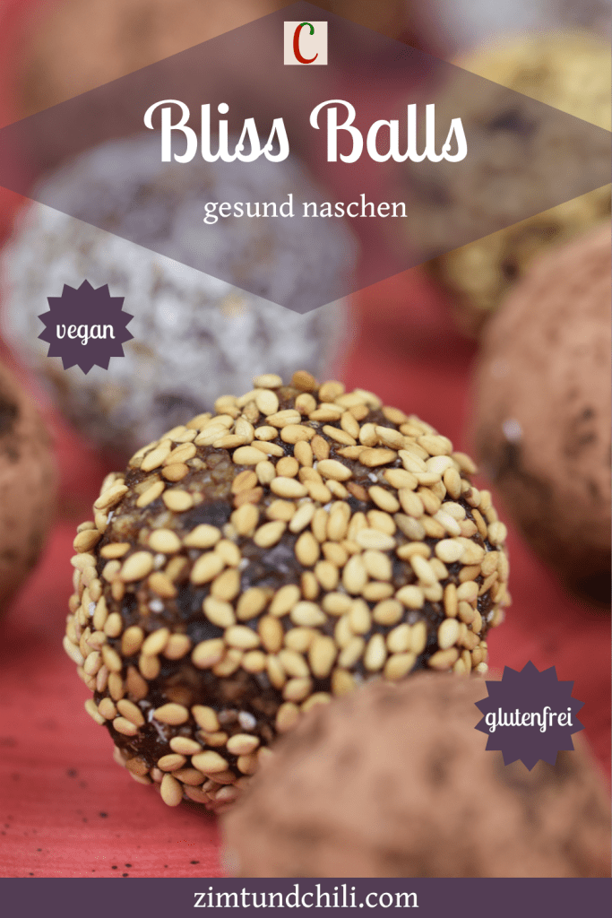 Glücksbällchen - Bliss Balls - ummantelt mit Kakaopuler, Kokosraspeln oder Sesam auf rotem Teller.
