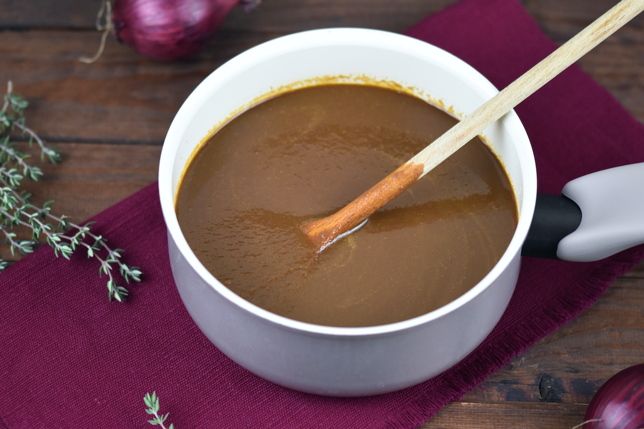 Würzige vegane Bratensauce in einem kleinen Topf. Hintergrund dunkel.