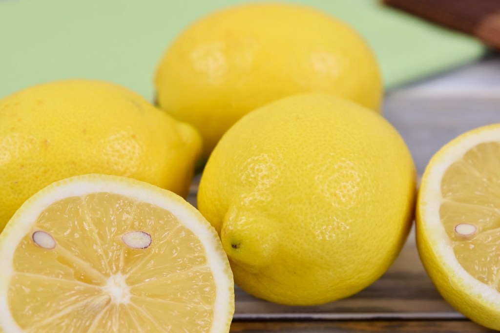 Mehrere Zitronen, eine ist aufgeschnitten. Hintergrund hell.