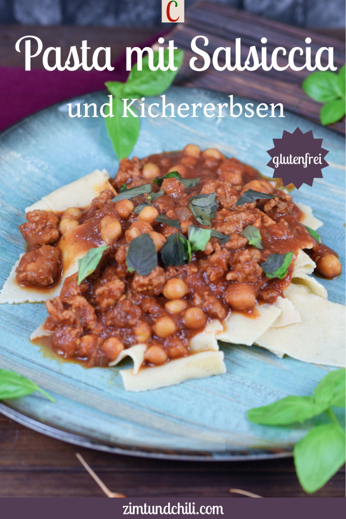 Pasta mit Salsiccia und Kichererbsen auf blauem Teller. Hintergrund dunkel. Beschrifteter Pin.