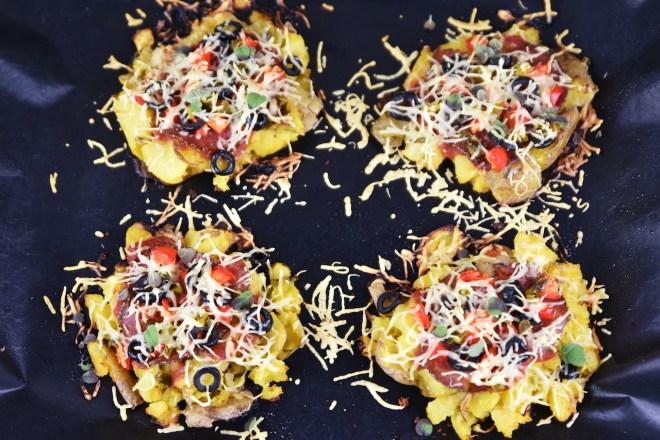 Pizza-Kartoffeln auf einem Backblech. Hintergrund dunkel.