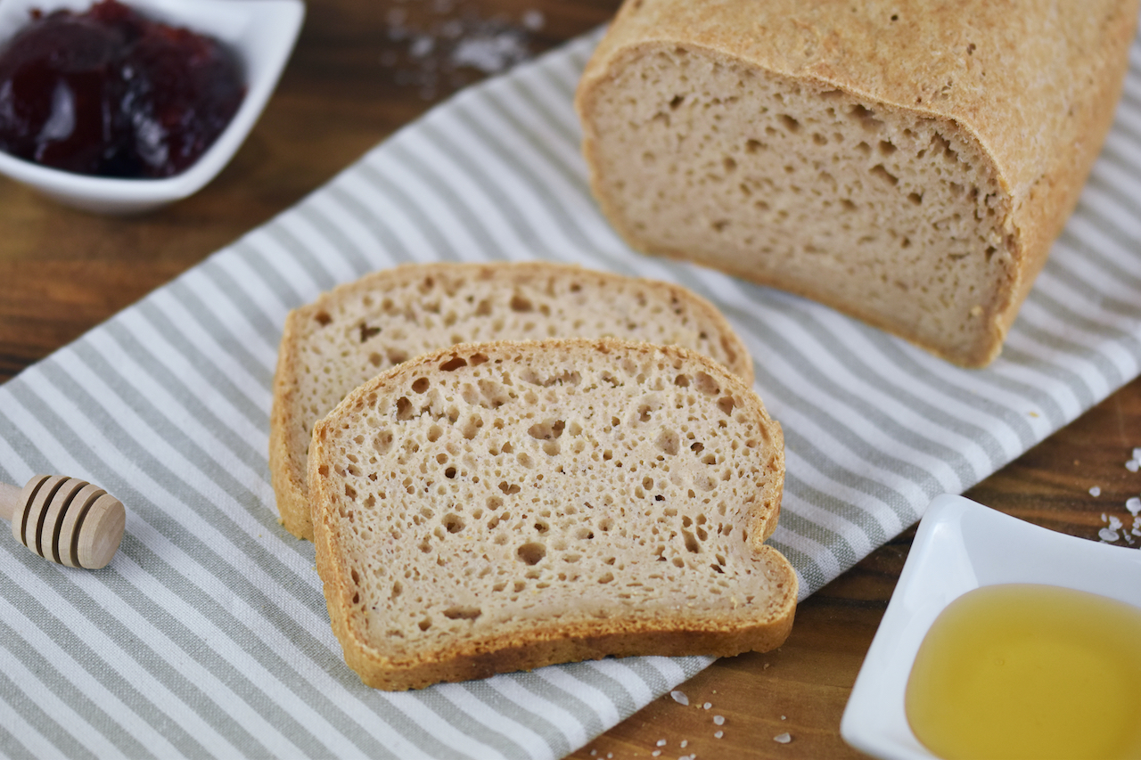 Glutenfreies Sandwichbrot teilweise angeschnitten auf Walnussbrett.