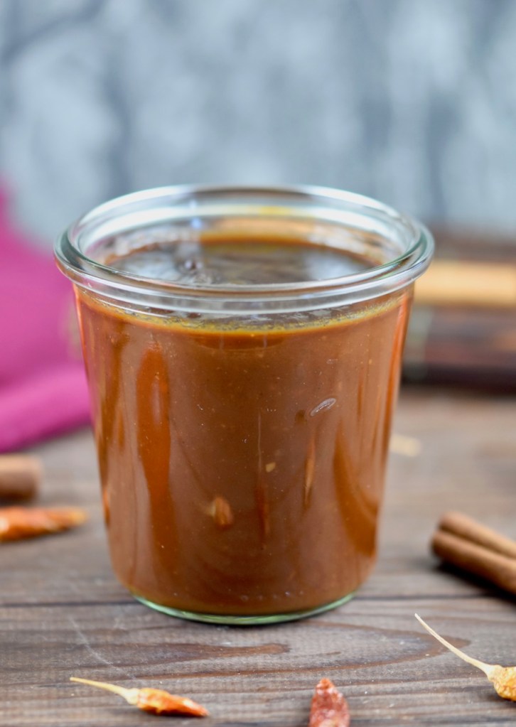 Rauchige BBQ-Sauce in einem Glas. Hintergrund dunkel.