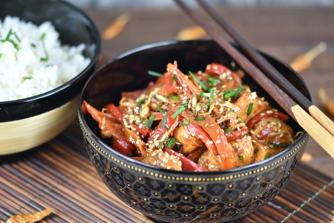 Bulgogi - koreanische Feuerpfanne in einer schwarzen Schale. Daneben steht Reis in einer anderen Schale.