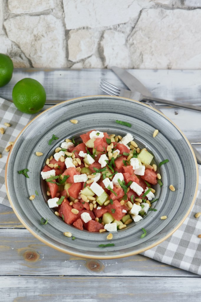Wassermelonen-Feta-Salat iauf einem grauen Teller. Hintergrund hell.