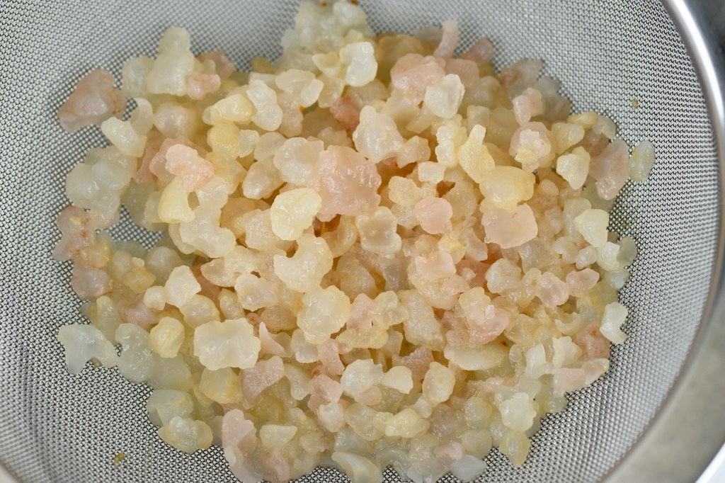 Wasserkefirkristalle in einem Sieb aus Edelstahl