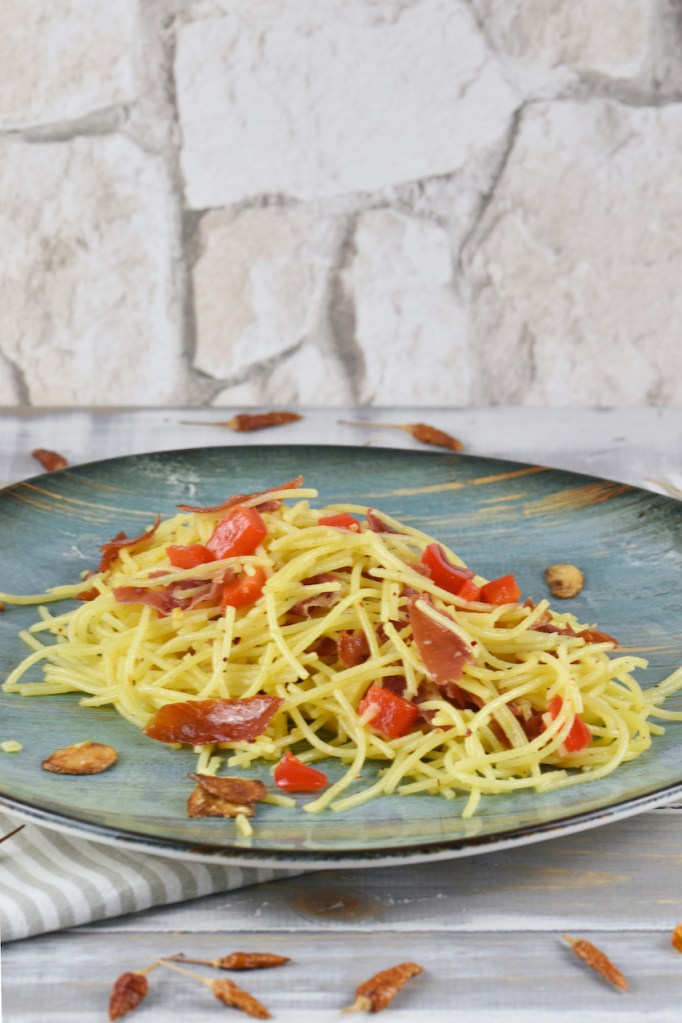 Spaghetti aglio e olio e peperoncino auf einem türkisen Teller.