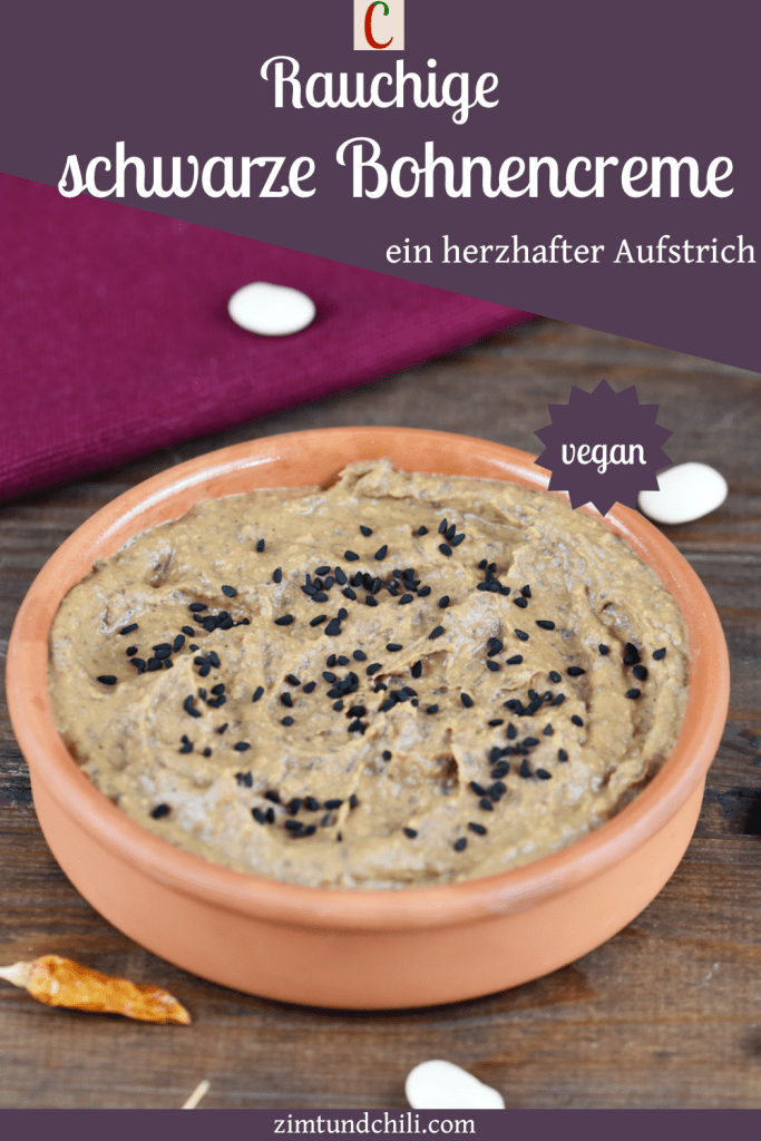 Rauchige schwarze Bohnencreme in einer Tonschale. Hintergrund dunkel. Beschrifteter Pin.