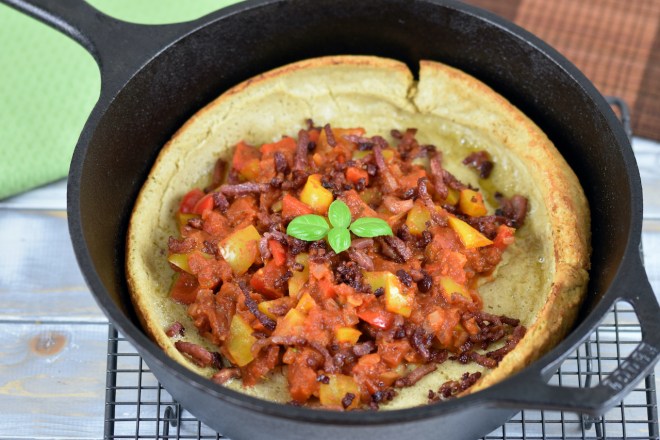 Herzhaftes Dutch Baby mit Paprikagemüse in einem schwarzen gusseisernen Topf.