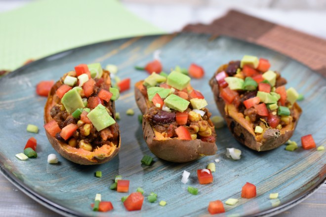 Gefüllte Süßkartoffel auf mexikanische Art dekoriert mit Paprika, Avocado und Frühlingszwiebeln.