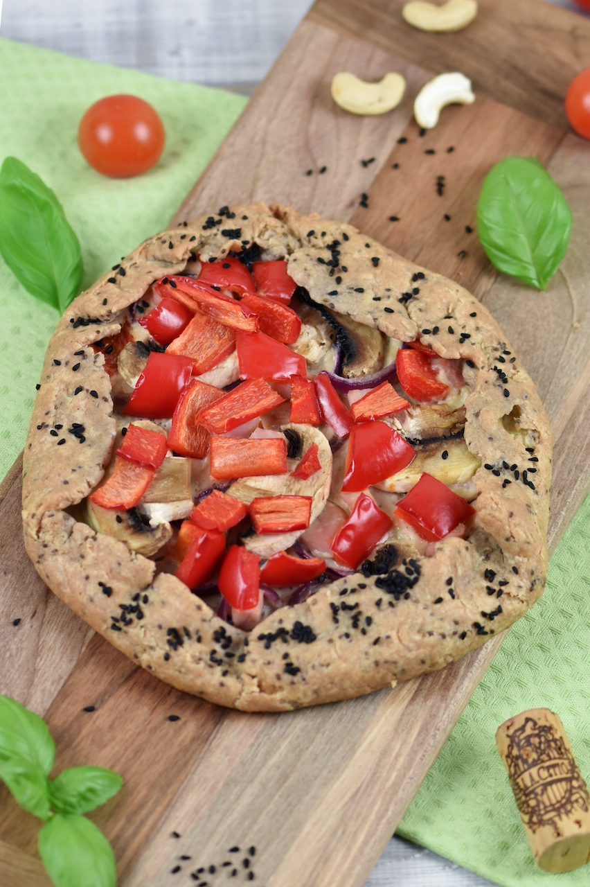 Knusprige Galette mit Paprika und Pilzen auf Holzbrett.