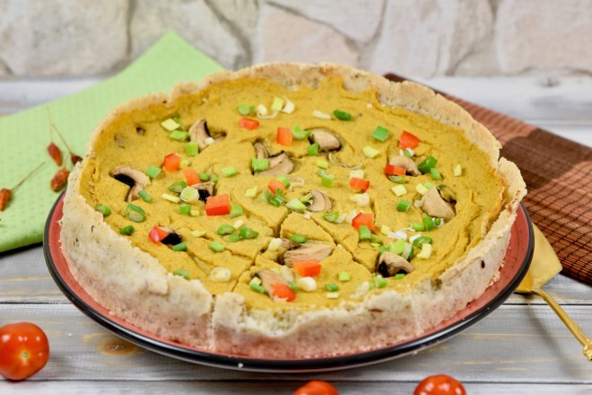 Glutenfreie Quiche mit Pilzen garniert mit Champignons, Paprika und Frühlingszwiebeln. Hintergrund hell.