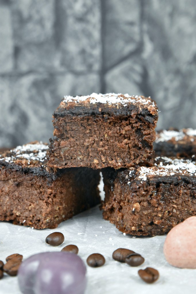 Vegane Brownies übereinander gestapelt auf Backpapier. Hintergrund dunkel.