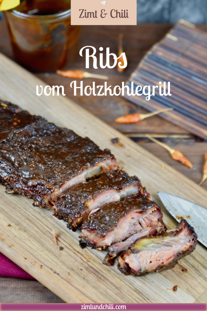 Ribs vom Holzkohlegrill auf Holzbrett. Ein Teil ist angeschnitten. Hintergrund dunkel. Pin beschriftet.
