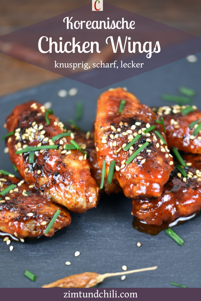 Koreanische Chicken Wings auf schwarzer Schieferplatte, garniert mit Schnittlauch und Sesam. Beschrifteter Pin.