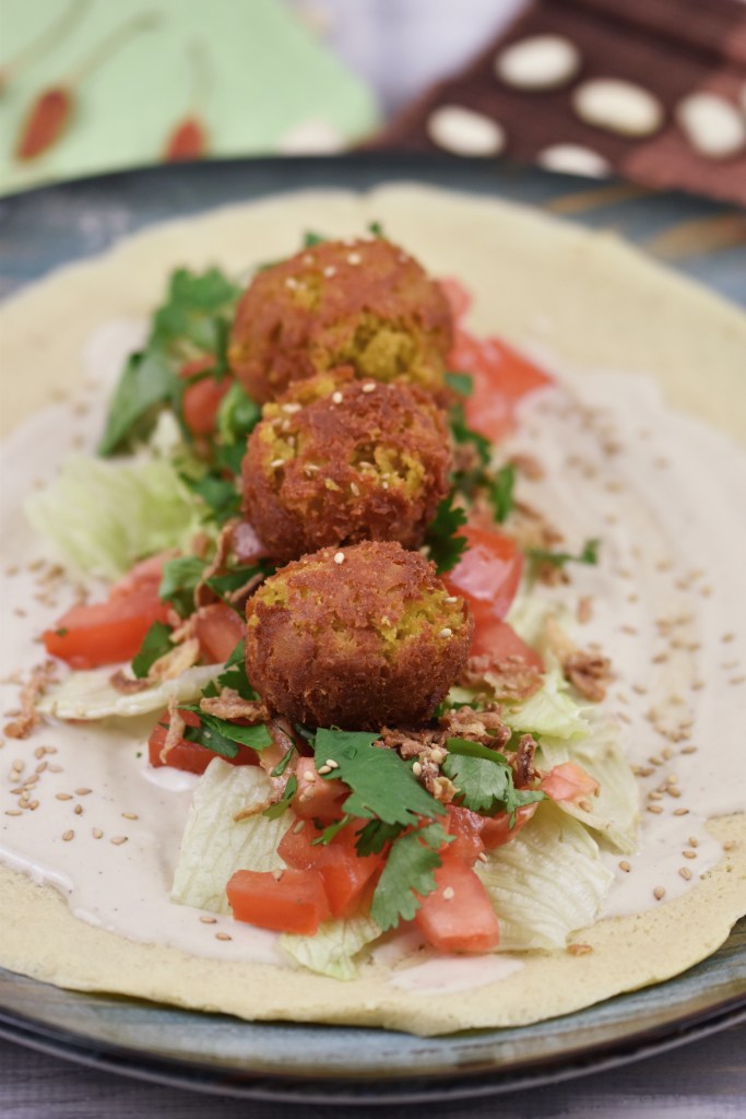 Falafel Wrap mit Gemüse, Salat und Sauce. Noch nicht aufgerollt.