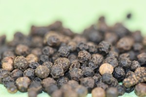 schwarze Pfefferkörner, Nahaufnahme, Hintergrund hellgrün
