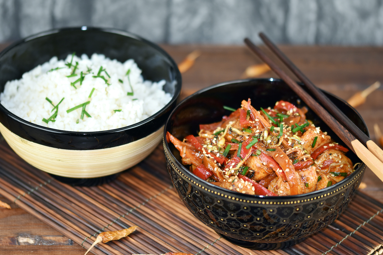 Bulgogi - koreanische Feuerpfanne in einer schwarzen Schale. Daneben steht Reis in einer anderen Schale.