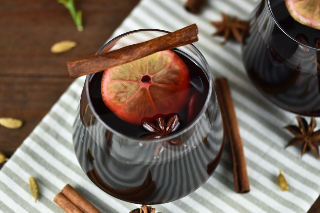 Klassischer Glühwein in 2 Gläsern auf hellem Tuch. Hintergrund dunkel.