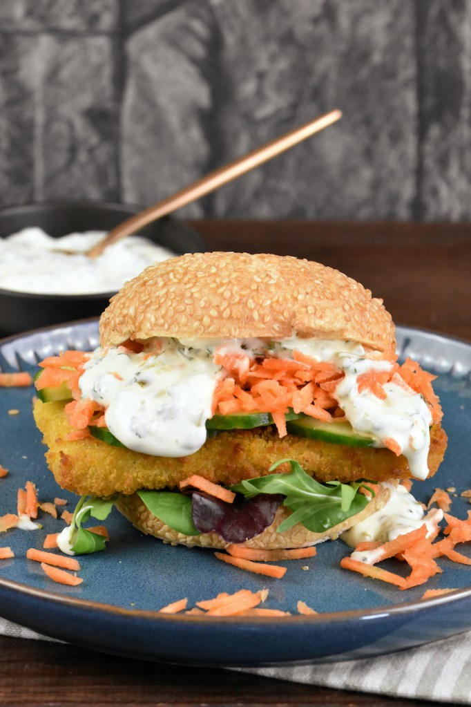 Veganer Fischburger mit Jalapeño-Remoulade auf blauem Teller.