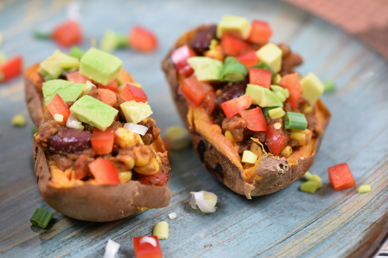 Gefüllte Süßkartoffel auf mexikanische Art dekoriert mit Paprika, Avocado und Frühlingszwiebeln.