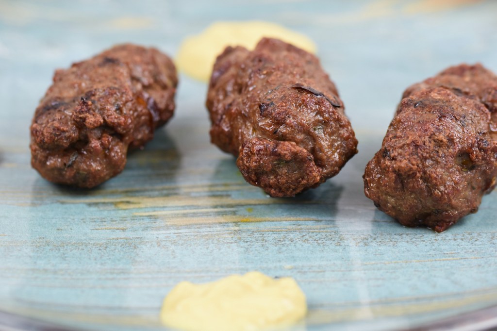 Mehrere Mici oder Mititei auf einem bläulichen Teller. Hintergrund hell.