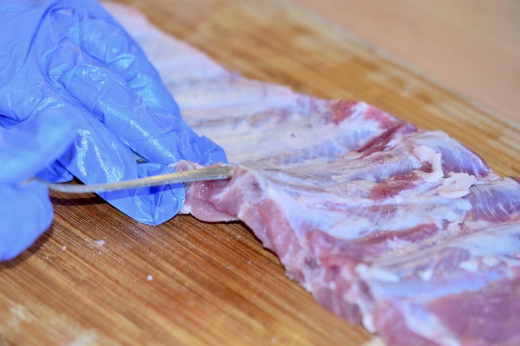 Der Stiel eines Teelöffels wird unter die Silberhaut von den Ribs geschoben.