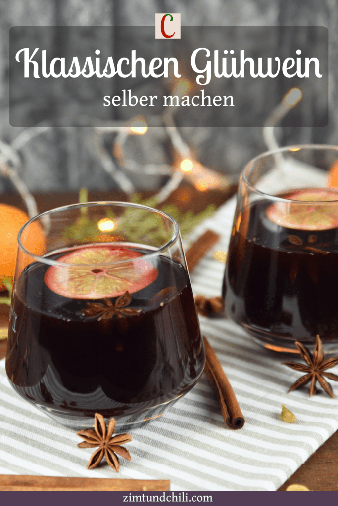 Klassischer Glühwein in 2 Gläsern auf hellem Tuch. Hintergrund dunkel. Beschrifteter Pin