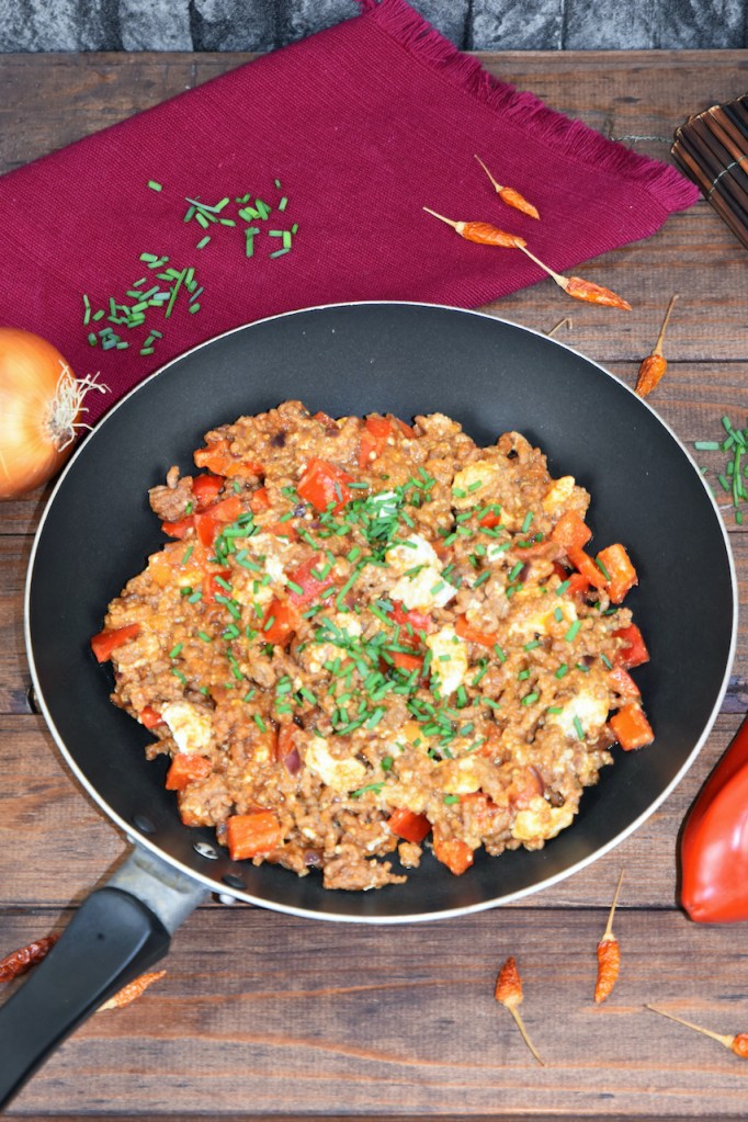Schnelle Hackfleischpfanne mit Paprika und Feta in einer Pfanne. Hintergrund dunkel.