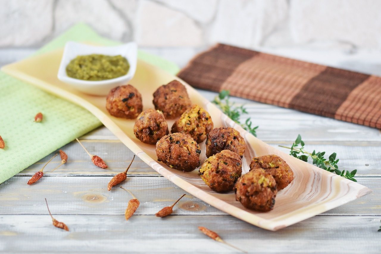 Möhren-Zucchini-Bällchen mit Jalapeño-Salsa auf länglicher Schale aus orangem Onyx.