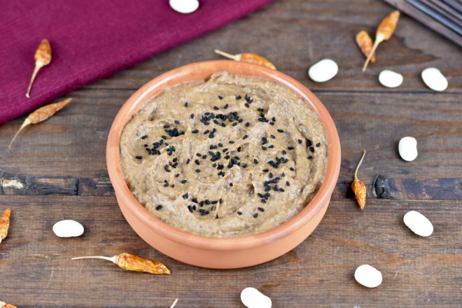 Rauchige schwarze Bohnencreme in einer Tonschale. Hintergrund dunkel.