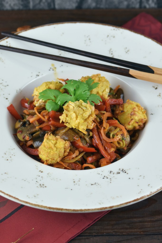 Asiatisches Wokgemüse mit knusprigem Tofu auf weißem Teller. Hintergrund dunkel.