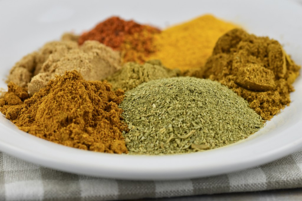 verschiedene Gewürze auf weißem Teller. Hintergrund hell.