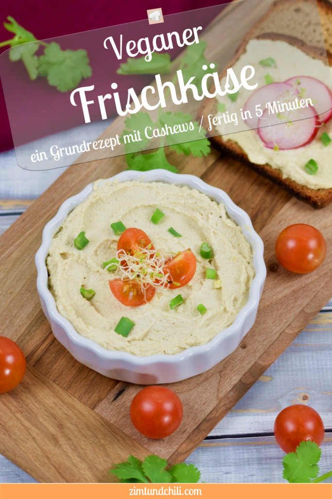 Veganer Frischkäse in weißer Schale, die auf einem Holzbrettchen steht. Der Frischkäse ist mit Vierteln von Cocktailtomaten, Frühlingszwiebel und Sprossen garniert. Im Hintergrund liegt eine Scheibe Brot mit Frischkäse und drei Scheiben Radieschen. Pin beschriftet