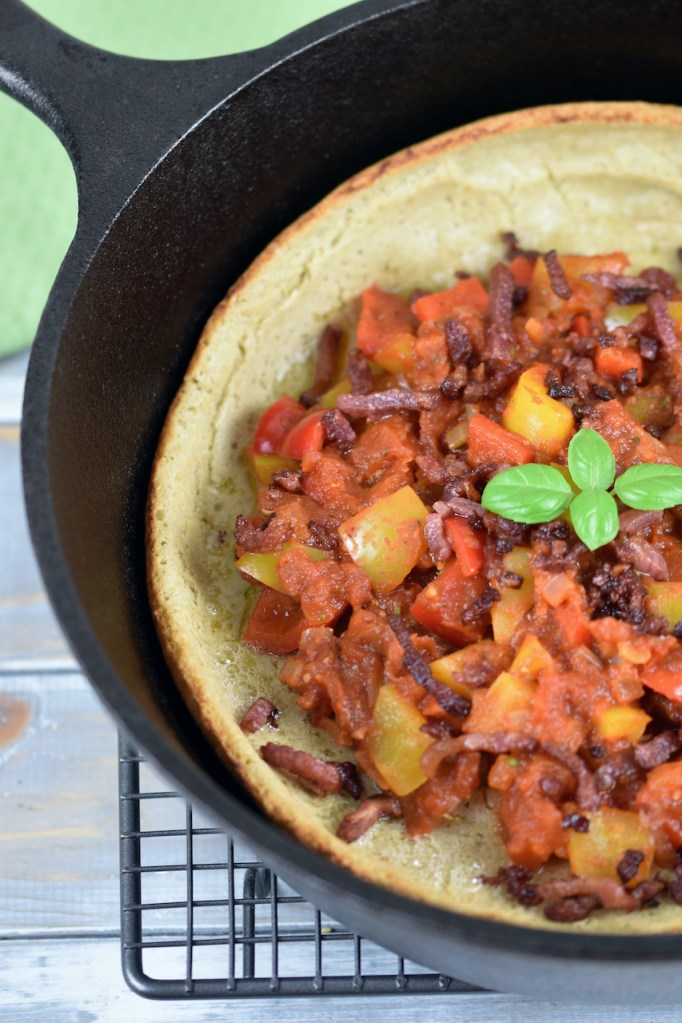 Herzhaftes Dutch Baby mit Paprikagemüse in einem schwarzen gusseisernen Topf. Der Topf ist nur zur Hälfte zu sehen.
