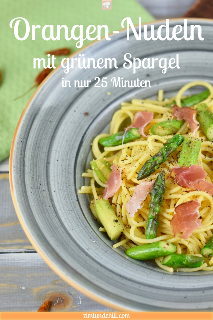 Orangen-Nudeln mit grünem Spargel in einem grauen tiefen Teller. Hintergrund hell. Pin beschriftet.