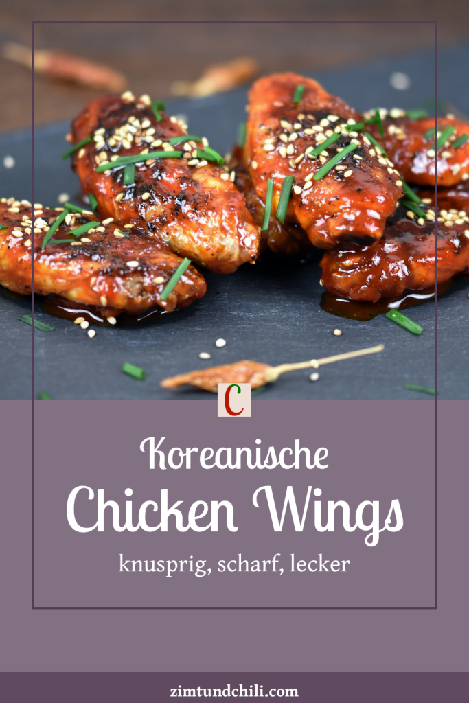 Koreanische Chicken Wings auf schwarzer Schieferplatte, garniert mit Schnittlauch und Sesam. Beschrifteter Pin.