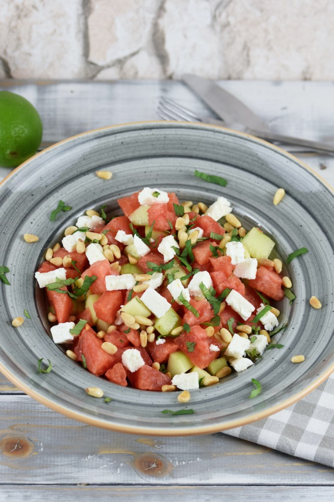 Wassermelonen-Feta-Salat iauf einem grauen Teller. Hintergrund hell.