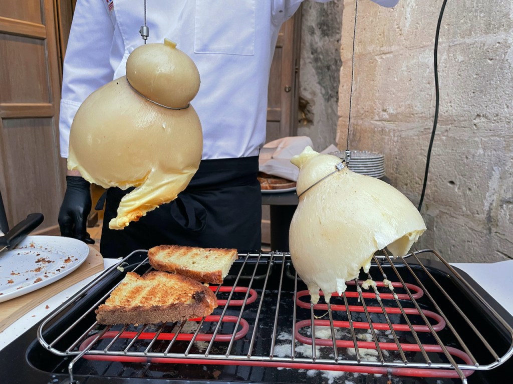 ganzer Käselaib, der in der Mitte aufgeschnitten über einem Grill hängt - Essen & Trinken in der Basilikata