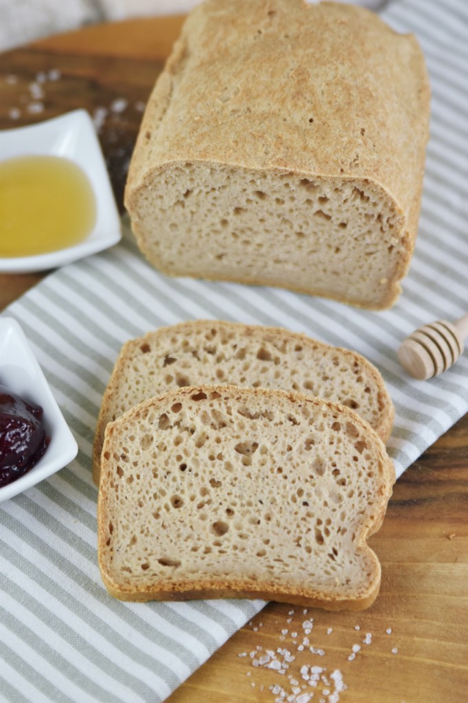 Glutenfreies Sandwichbrot teilweise angeschnitten auf Walnussbrett.