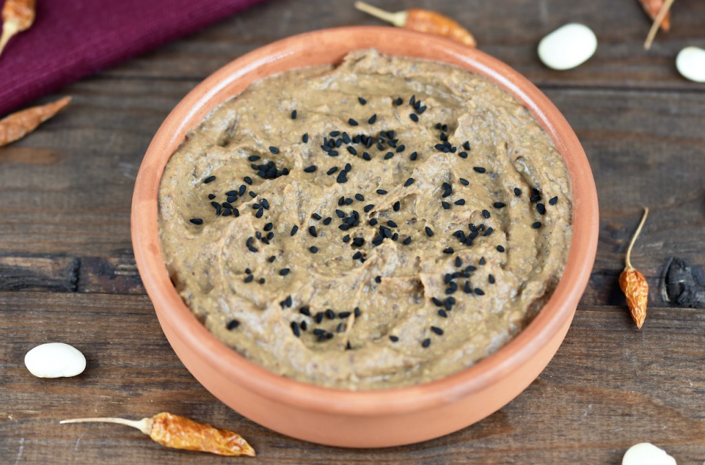 Rauchige schwarze Bohnencreme in einer Tonschale. Hintergrund dunkel.