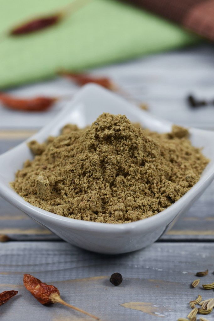 Chat Masala in weißer Schale. Heller Hintergrund, dekoriert mit Gewürzen.