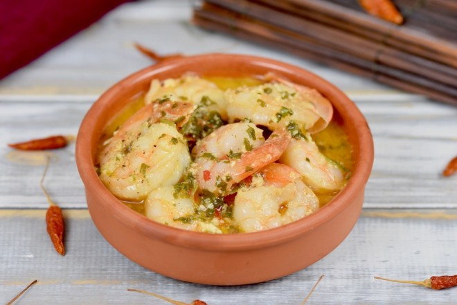 Gambas al Pil Pil in einer Knoblauch-Weißwein-Sauce in einer Tonschale. Hintergrund hell.