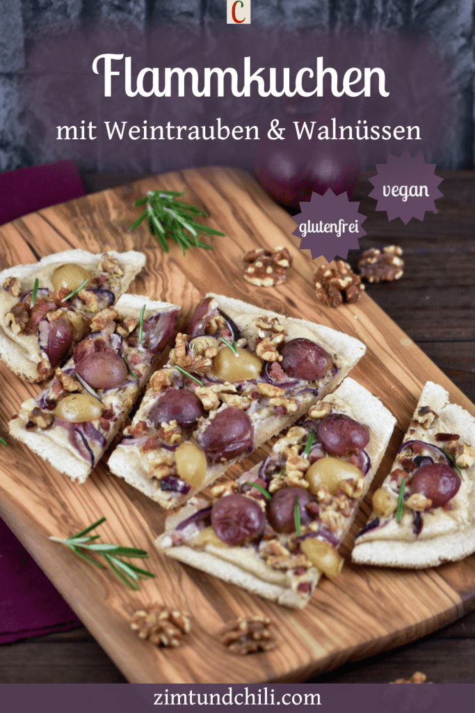 Flammkuchen mit Weintrauben und Walnüssen in Stücke geschnitten auf einem Holzbrett. Beschrifteter Pin.