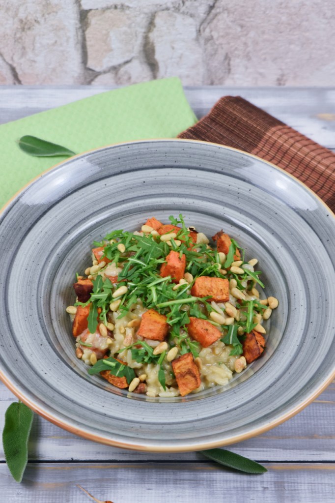 Risotto mit Süßkartoffeln und Rucola auf grauem Teller.