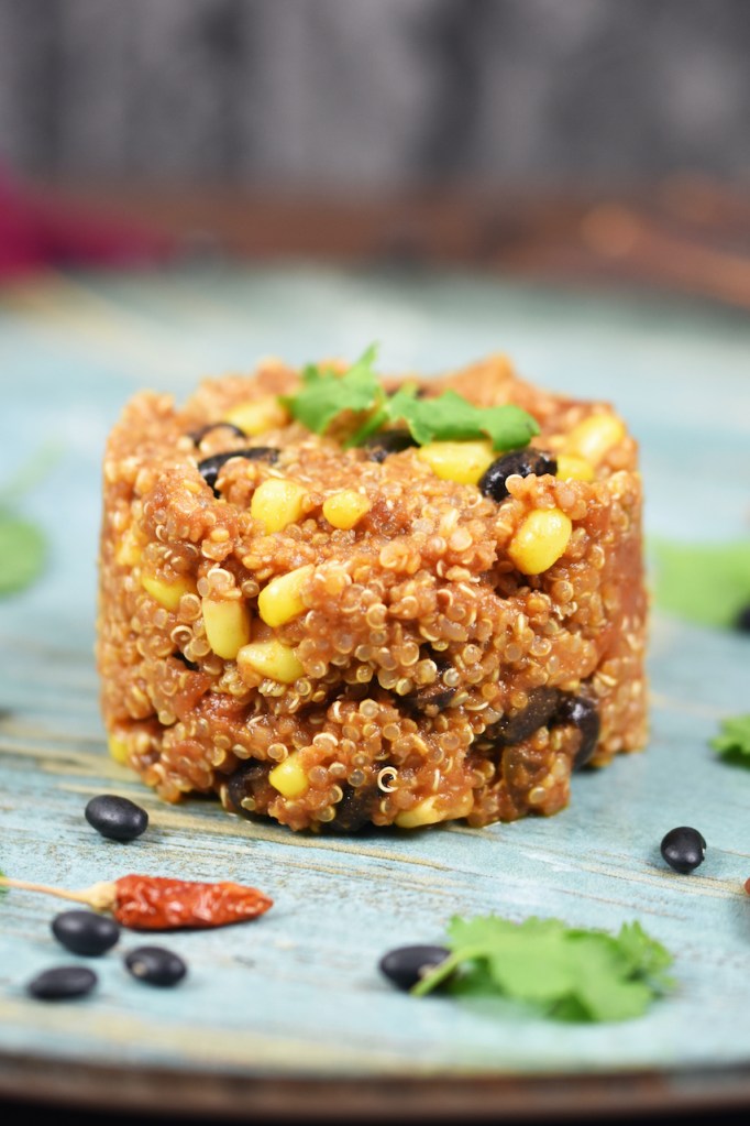 Quinoa-Pfanne auf mexikanische Art auf blauem Teller. Hintergrund dunkel.