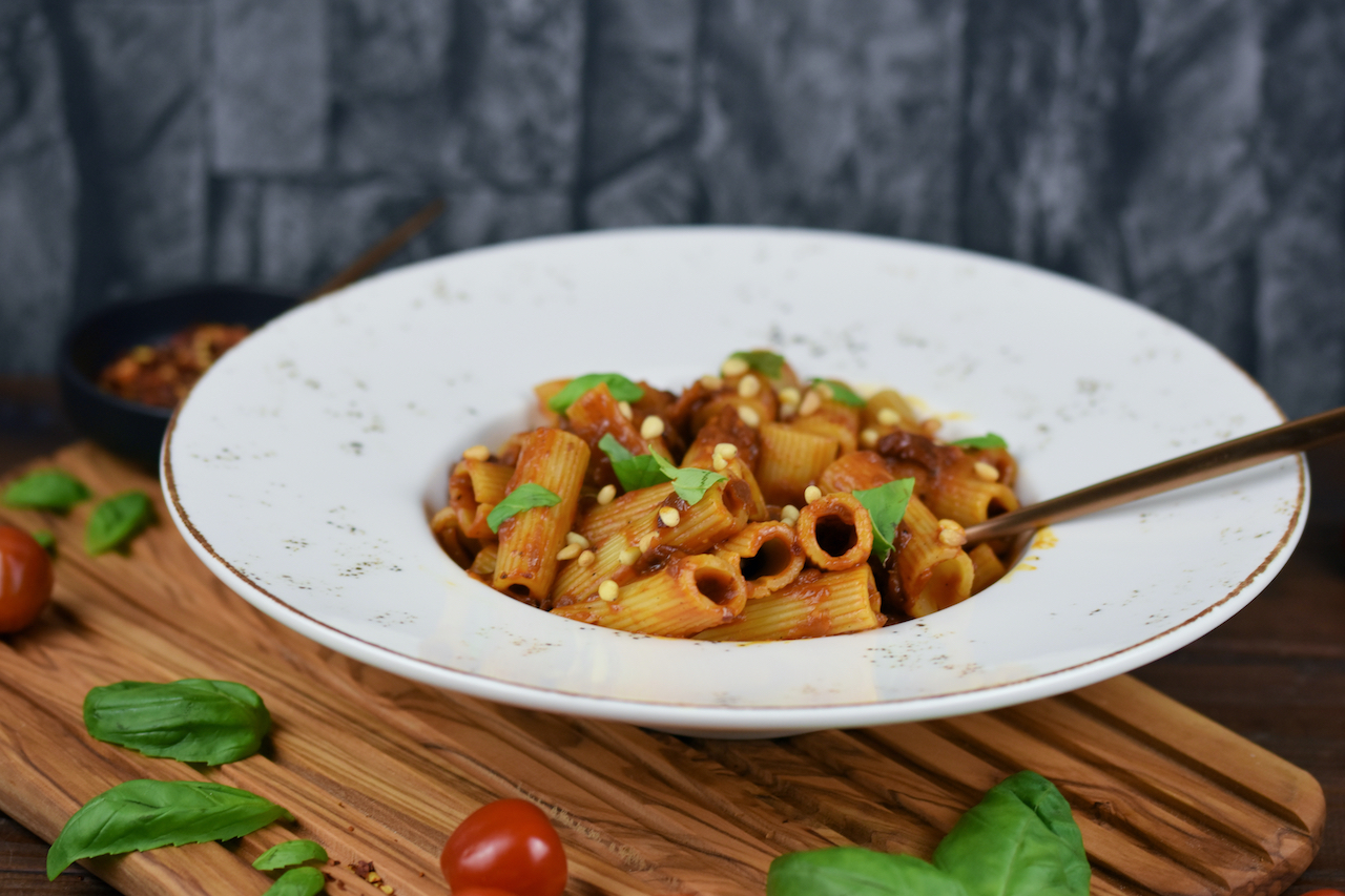 Pasta mit karamellisierten Zwiebeln auf weißem Teller. Hintergrund dunkel.
