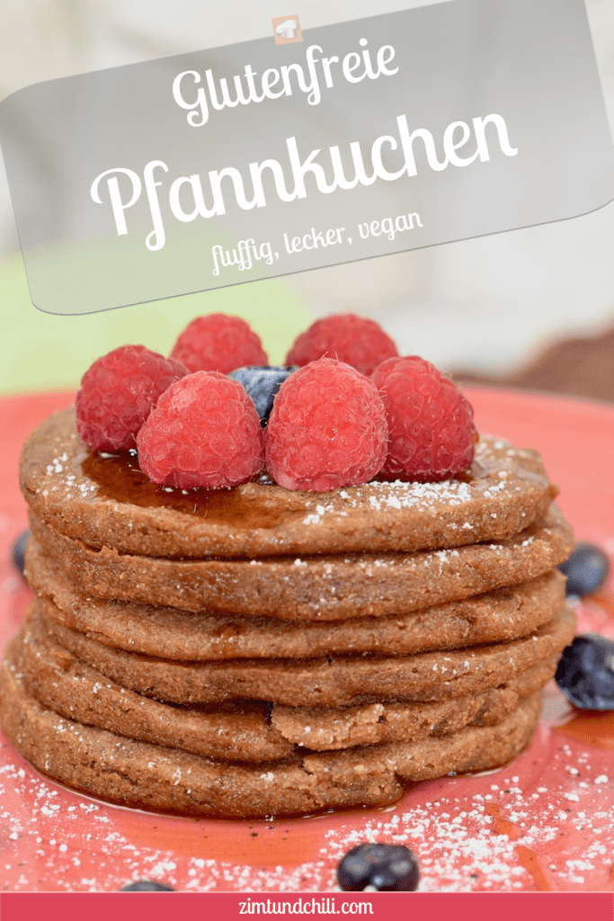 Glutenfreie Pfannkuchen gestapelt auf roten Teller, garniert mit Himbeeren, Blaubeeren, Ahornsirup und Puderzucker. Hintergrund hell. Nahaufnahme. Beschrifteter Pin