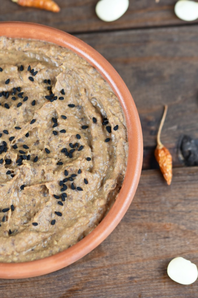 Rauchige schwarze Bohnencreme in einer Tonschale halb zu sehen. Hintergrund dunkel.